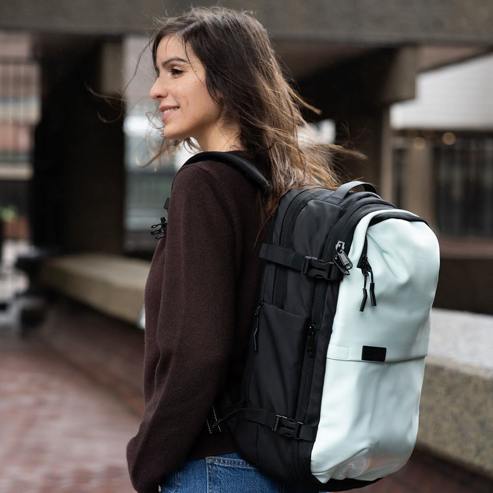 街のテラスで、パステルブルーの Backvac Pro を背負う女性