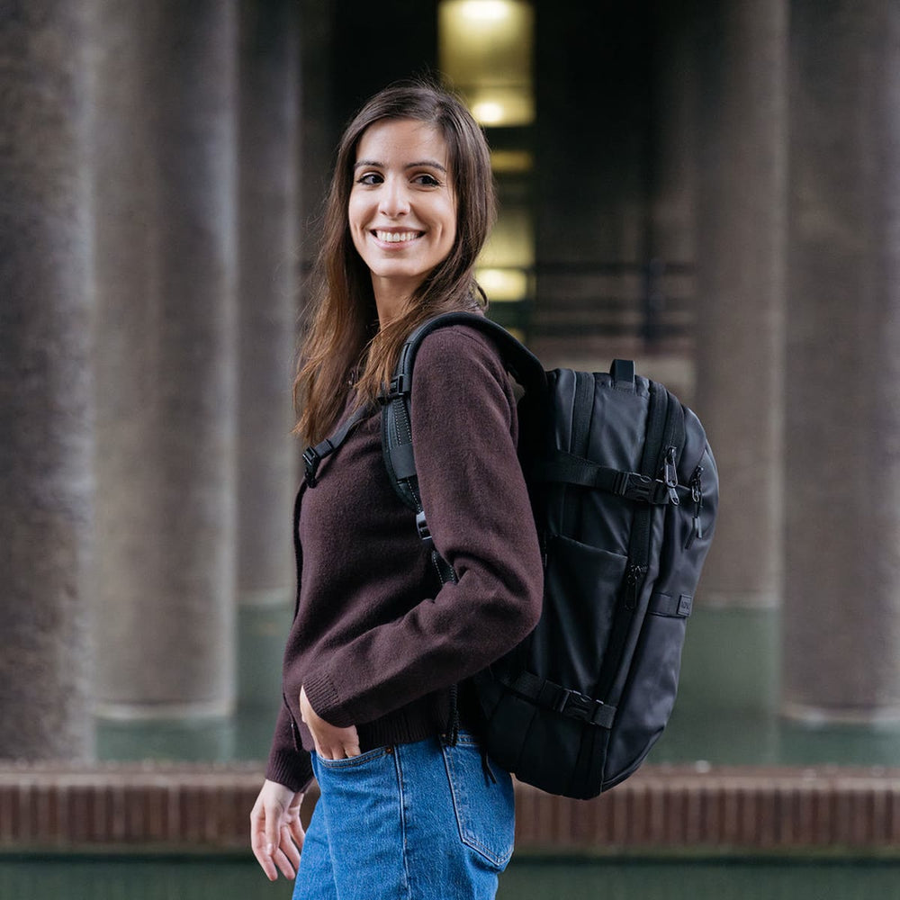 コンクリートの柱のそばで、マットブラックの Backvac Pro を背負う女性