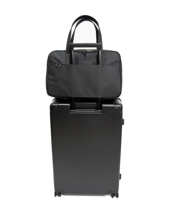 Backvac Overnight Bag sobre uma mala, com zoom no encaixe para mala passado pela alça