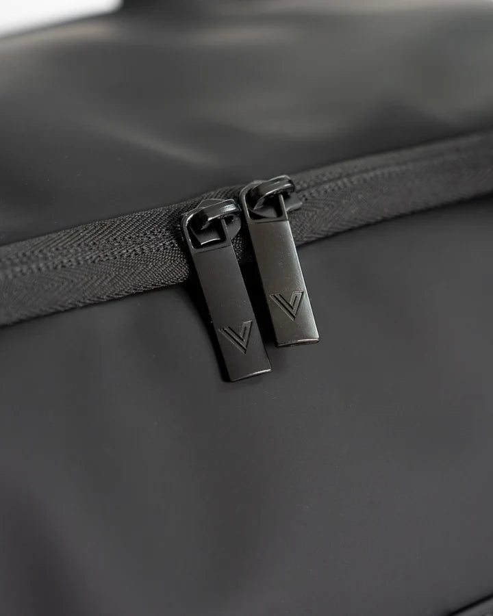 Close do nylon revestido, fosco e resistente à água da Overnight Bag, ao lado dos puxadores do zíper